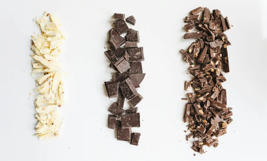 Three piles of chopped chocolate on white background.