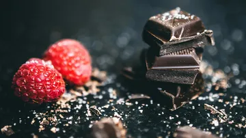 Schokoladenstücke mit Himbeeren auf einem Tisch.