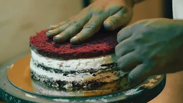 Hands layering cake with frosting inside.