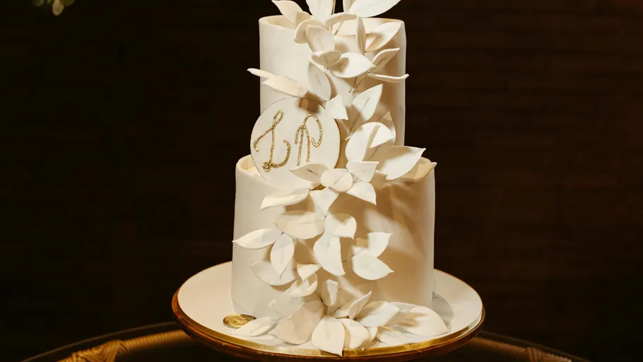 Dreistöckige weiße Torte mit Dekoblättern.