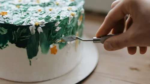 Hand dekoriert Kuchen mit grünem Zuckergussblumen.