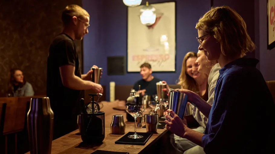 People making cocktails in a dimly lit bar.