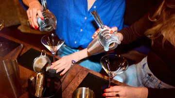 Zwei Frauen gießen Getränke in Martini-Gläser.
