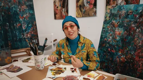 Frau malt abstrakte Kunst im bunten Studio.