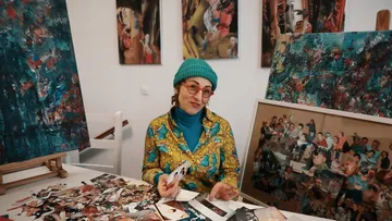 Woman creating collage at art studio table.