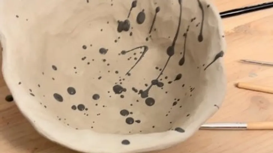Ceramic bowl with black paint splatters.