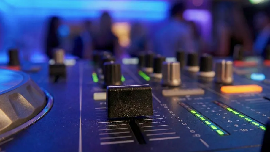Audio mixer with glowing lights in club.
