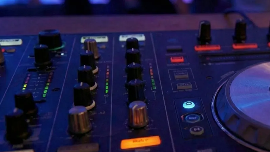 DJ mixer with glowing buttons in club.