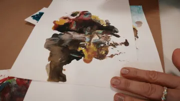 Person holding abstract painting on paper.