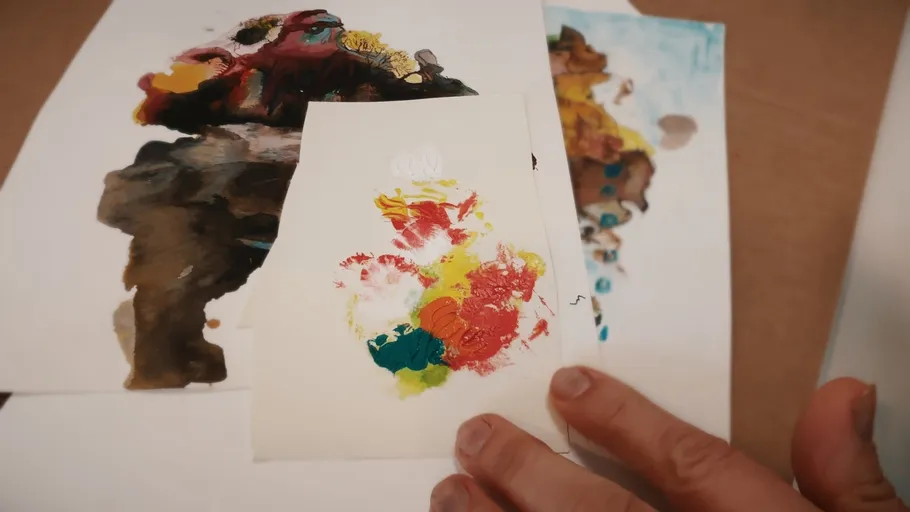 Hands holding colorful abstract paintings.