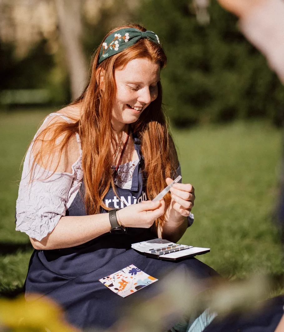 Woman painting outdoors in sunlight with palette.