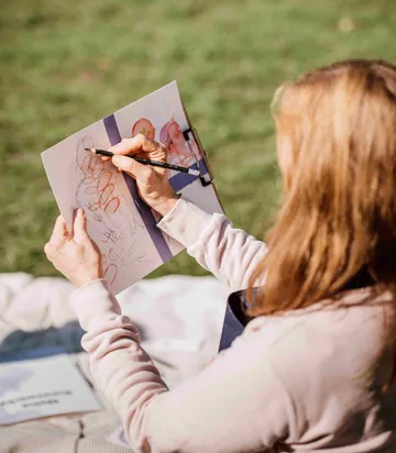 Person skizziert auf Papier im Park.