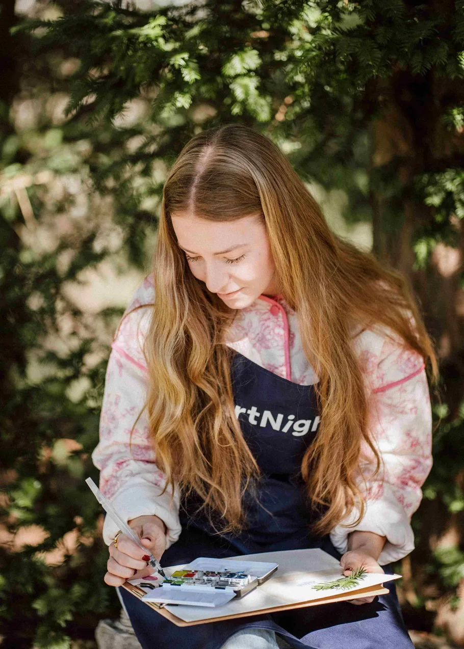 Woman painting outdoors with plants around.