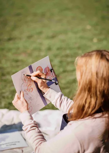 Person sketching outdoors on a sunny day.