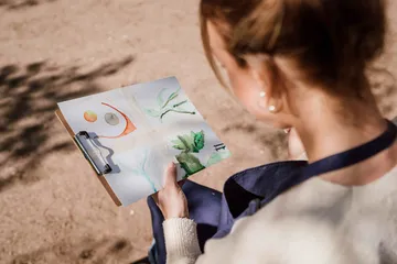 Woman holding clipboard with watercolor paintings.