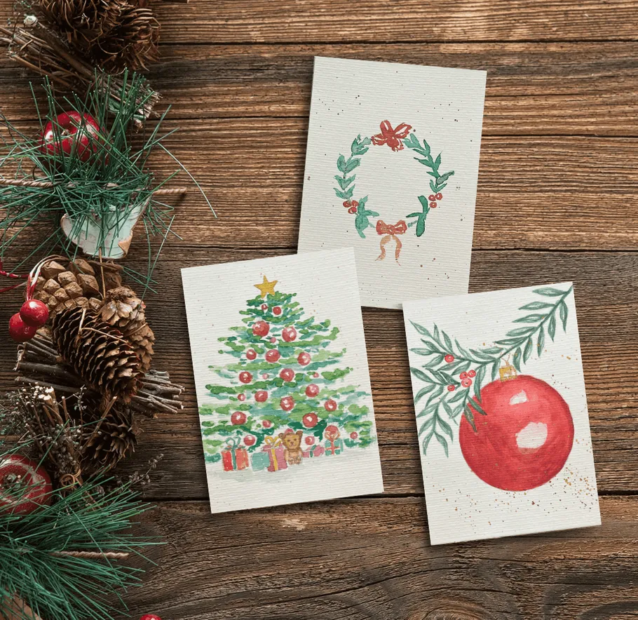 Christmas cards on wooden table with pinecones.
