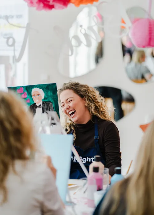 Woman laughing while painting at art class.