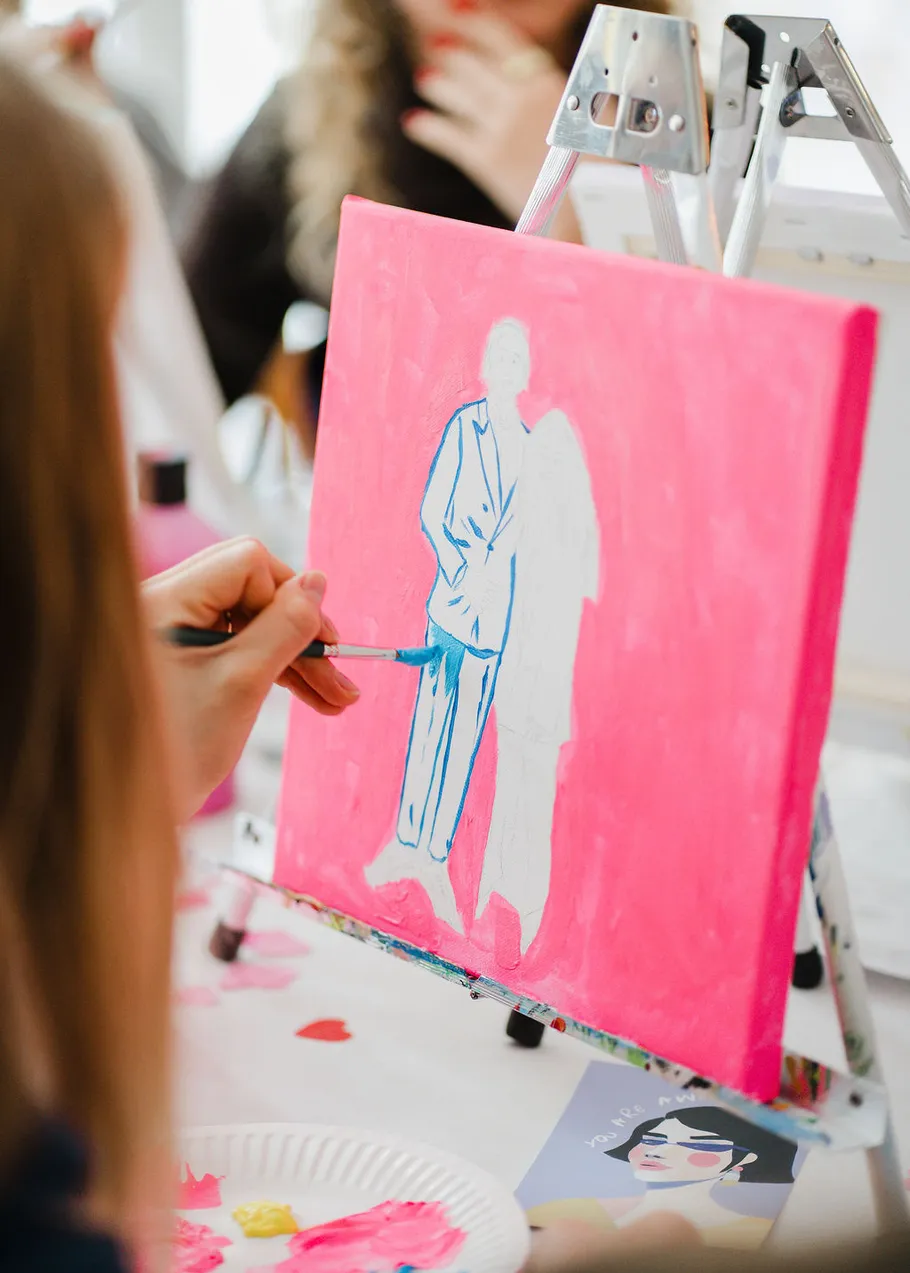 Person painting blue suit on pink canvas.