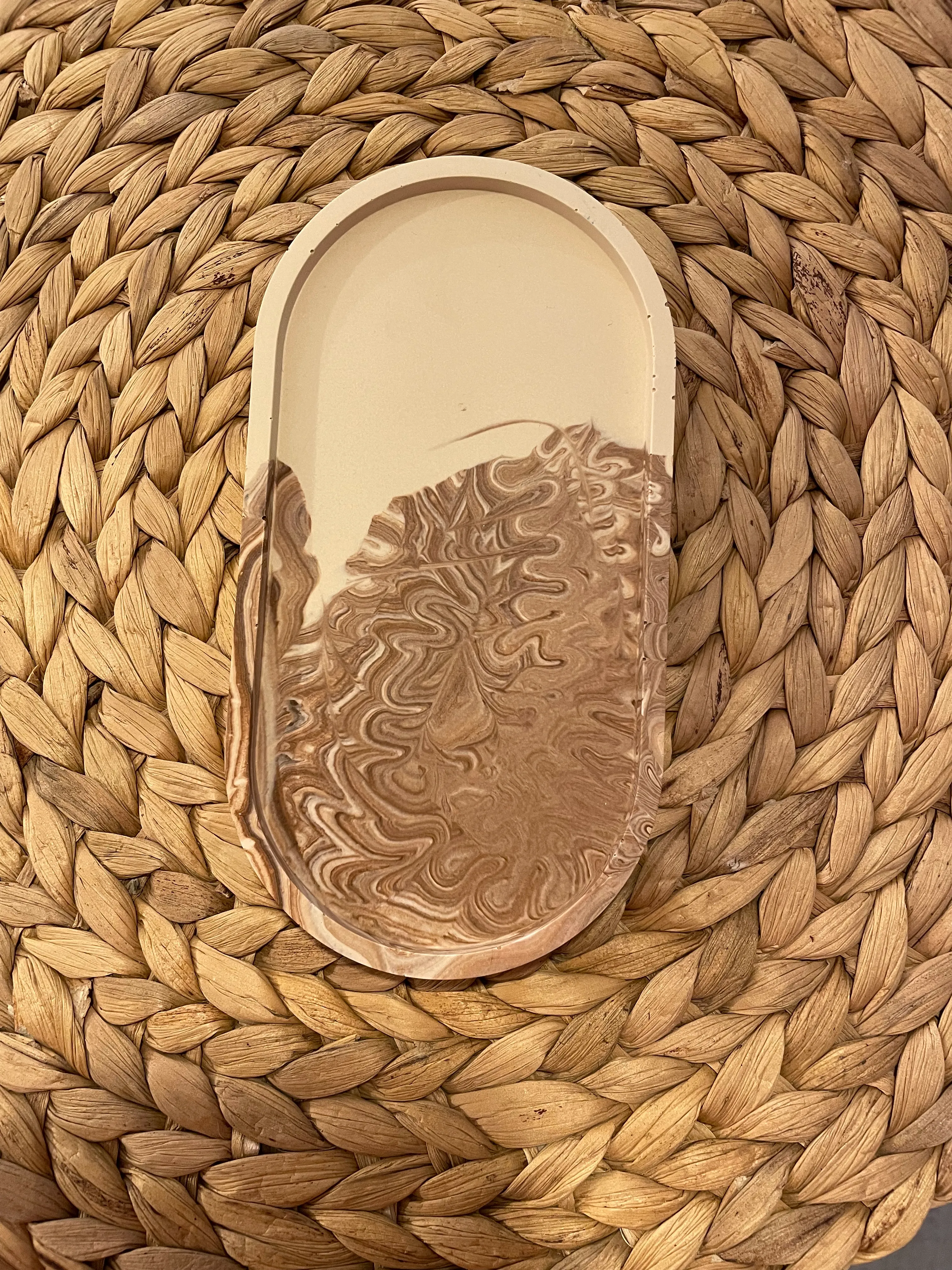 Ovales Tablett mit Marmorierung auf geflochtener Matte.