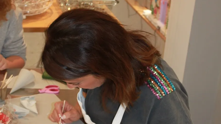 Person decorating cookies at a table.