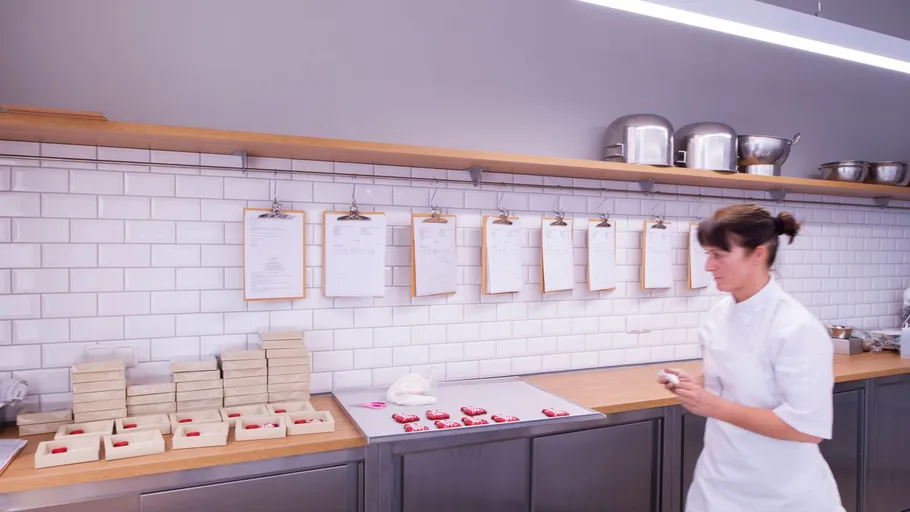 Person arranging pastries in a kitchen.