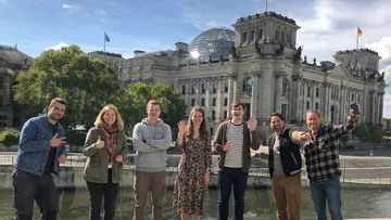 Sieben Personen posieren vor dem Reichstagsgebäude.