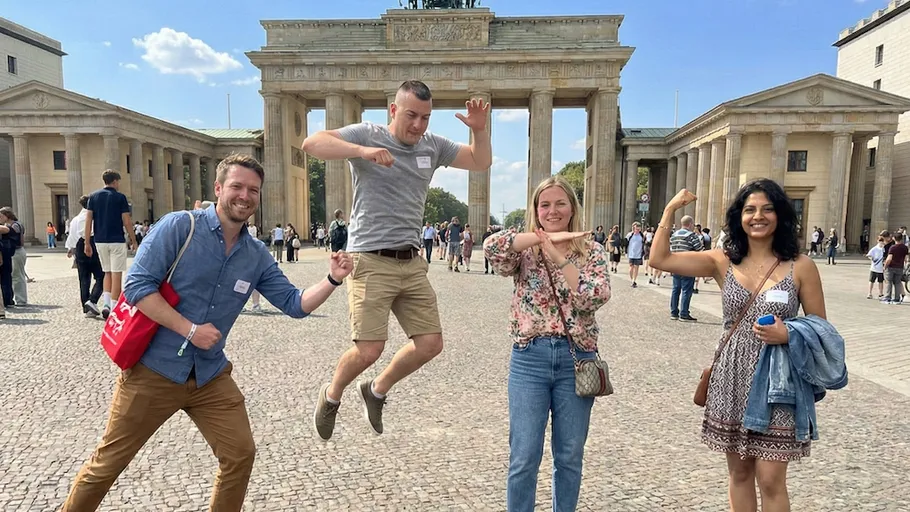 Vier Personen posieren begeistert vor dem Brandenburger Tor.