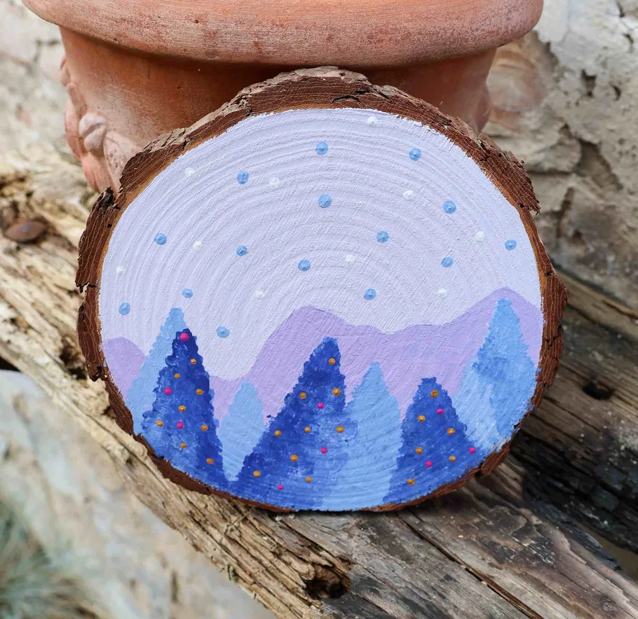 Painted wood slice with winter trees scene.