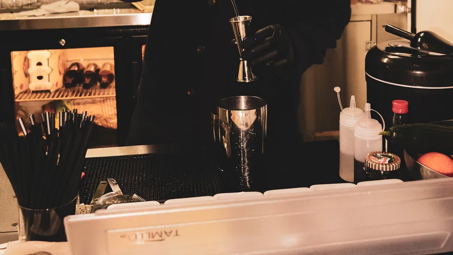 Bartender mixing drink at bar counter.
