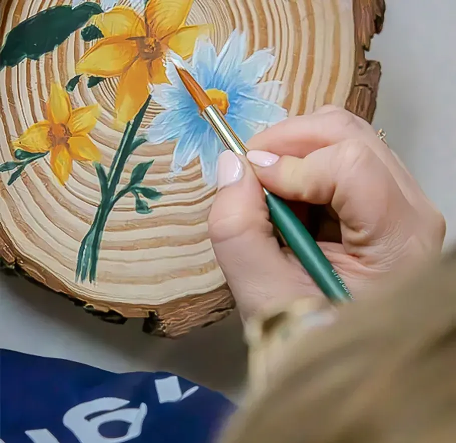 Hand malt Blumen auf einem Holzkreis.