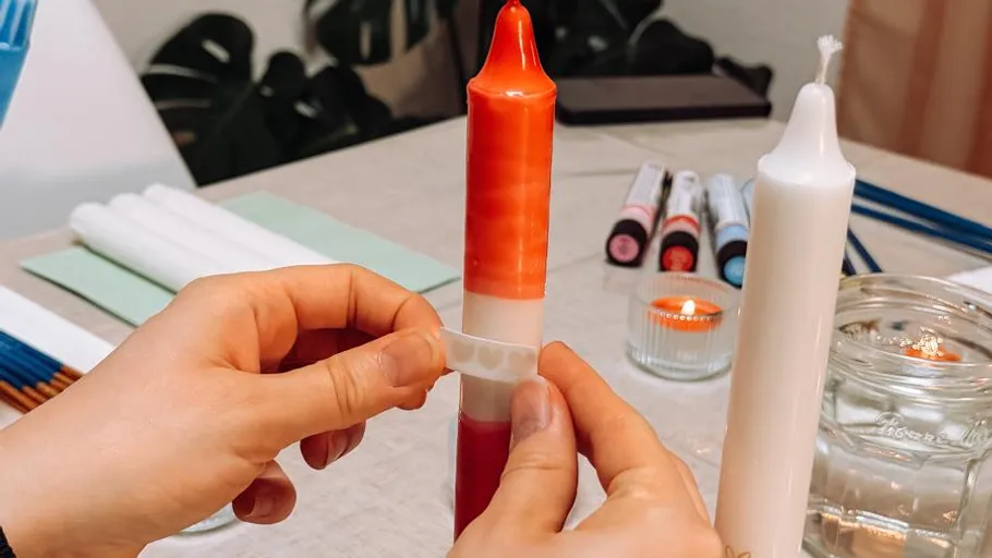 Hände dekorieren Kerzen auf Tisch.