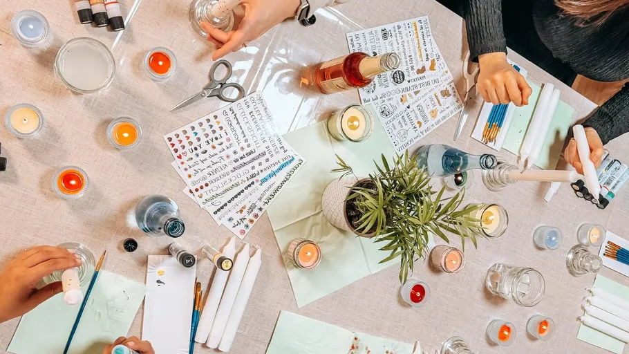 Hands crafting candles on a table.