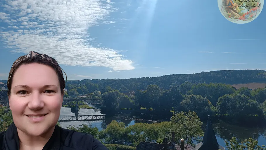 Frau lächelt mit Flusslandschaft im Hintergrund.