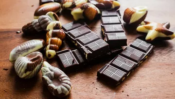 Chocolate bars and seashell shapes on wooden surface.