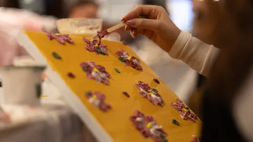 Hand painting flowers on canvas indoors.