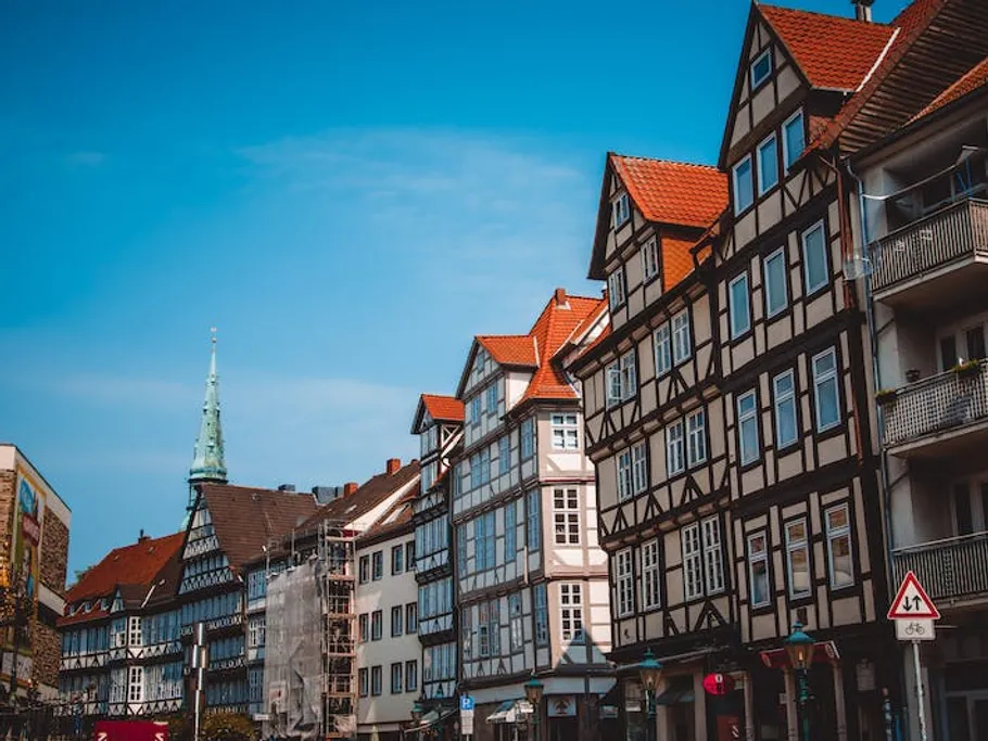 Half-timbered houses stand in a picturesque urban landscape under blue skies.
