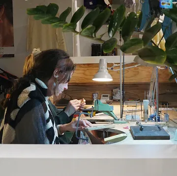 Zwei Personen fertigen Schmuck in einer Werkstatt.