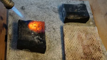 Torch heating metal on a block surface.