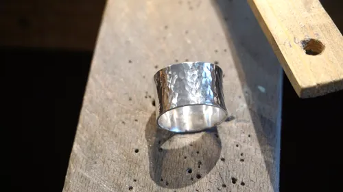 Silberring auf Holzoberfläche, wirft Schatten.