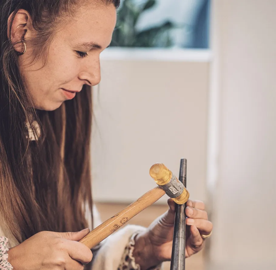 Woman hammering metal in a workshop.