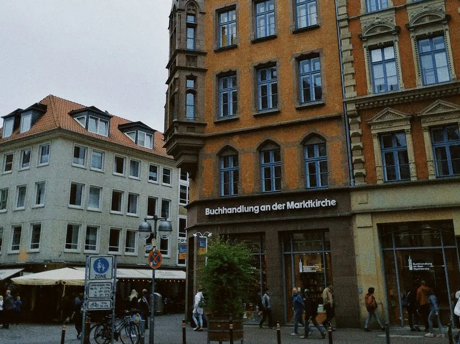 Buchhandlung in Stadt, Menschen gehen vorbei und sitzen draußen.