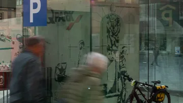 Verschwommene Menschen gehen an Glas vorbei, Fahrrad in Nähe.
