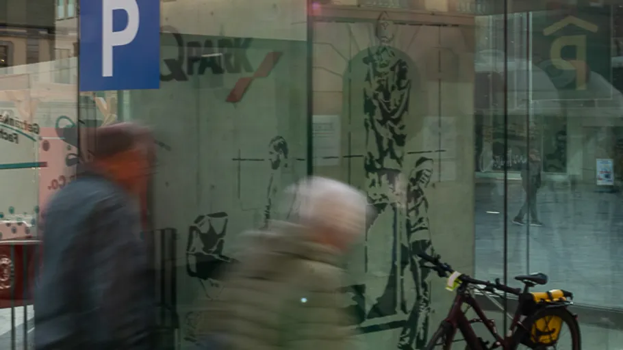 Blurred people walking by glass, bike nearby.