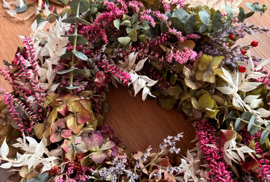 Colorful floral wreath on wooden table.