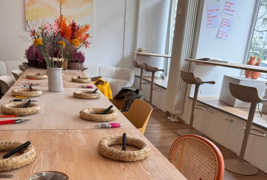 Table with crafting setup, flowers decorate room.