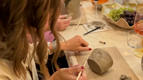 Women sculpting clay while seated at table.