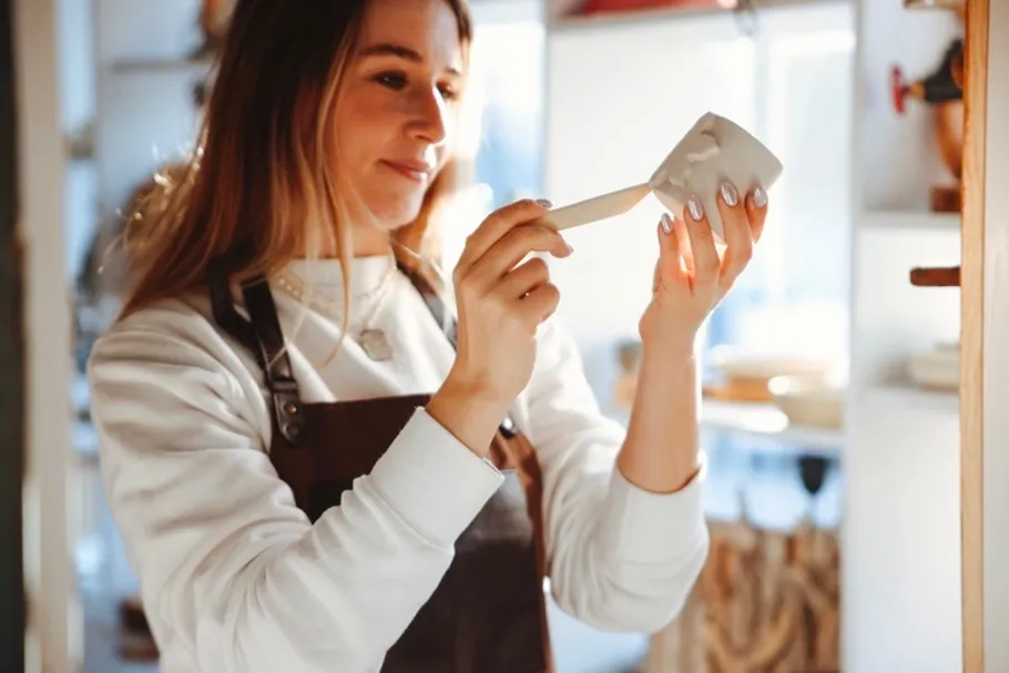 Frau töpfert Keramik in sonnigem Atelier.