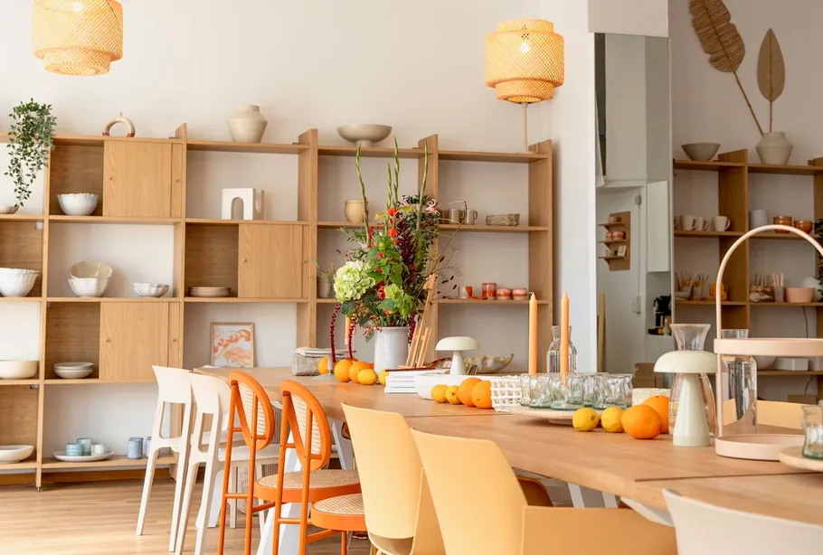 Esszimmertisch mit Orangen, Regale im Hintergrund.