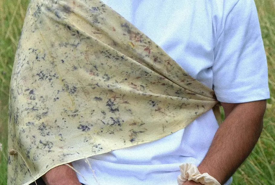 Person holding marbled fabric in grassy field.