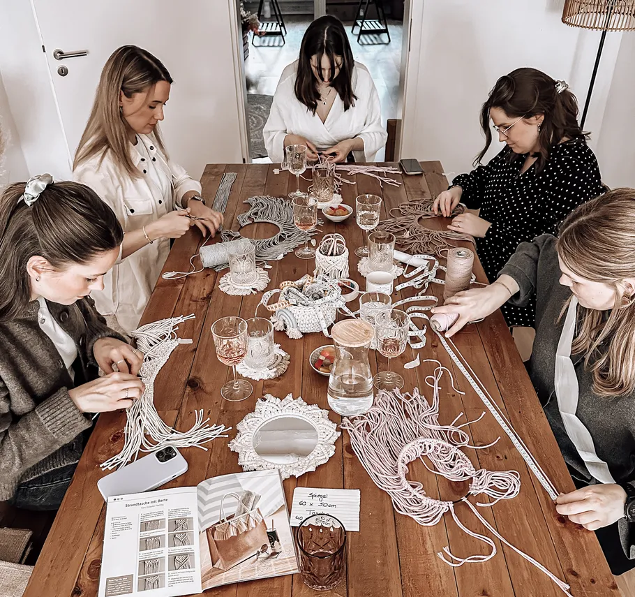Group of women crafting at a wooden table.